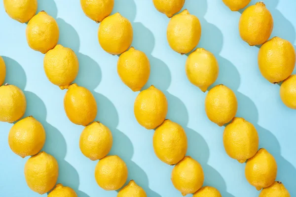Pattern of ripe yellow lemons on blue background with shadows — Stock Photo