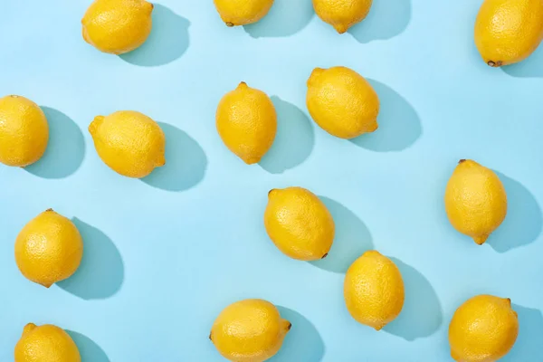 Top view of ripe yellow lemons on blue background with shadows — Stock Photo