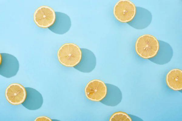 Vue de dessus des citrons jaunes coupés mûrs sur fond bleu — Photo de stock