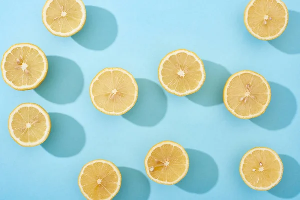 Vista superior de limones amarillos cortados maduros sobre fondo azul - foto de stock