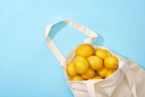 Vue du dessus des citrons jaunes mûrs dans un sac écologique en coton sur fond bleu — Photo de stock