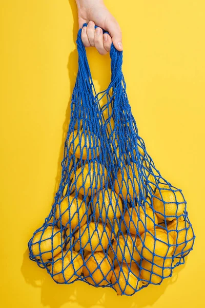 Top view of ripe lemons in string bag on yellow background — Stock Photo