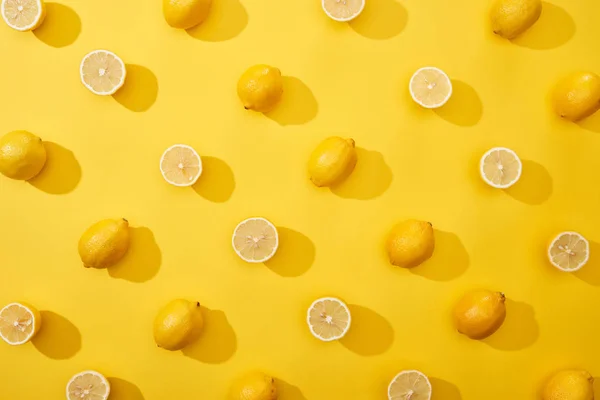Vista superior de corte maduro y limones enteros sobre fondo amarillo - foto de stock