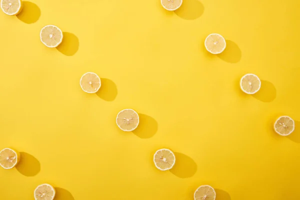 Vista superior de limones cortados maduros sobre fondo amarillo - foto de stock