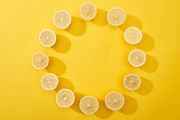 Limoni tagliati maturi su tagliere di legno su fondo giallo — Foto stock