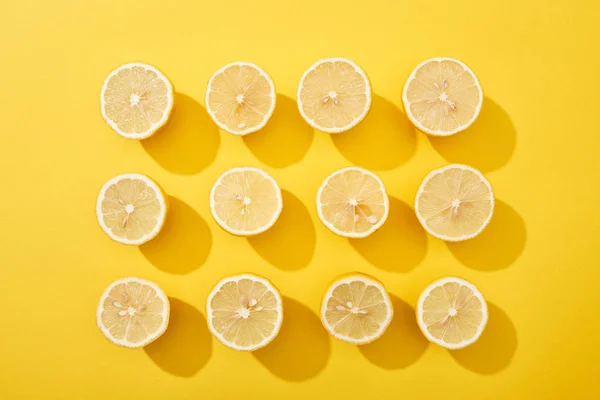 Tendido plano con limones cortados maduros sobre fondo amarillo - foto de stock