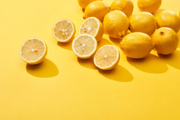 Corte maduro y limones enteros sobre fondo amarillo - foto de stock