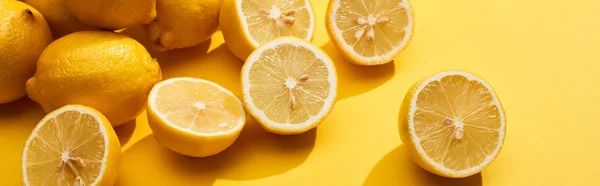 Corte maduro y limones enteros sobre fondo amarillo, plano panorámico - foto de stock