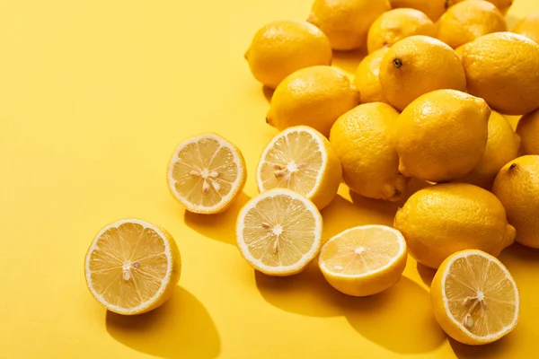 Coupe mûre et citrons entiers sur fond jaune — Photo de stock