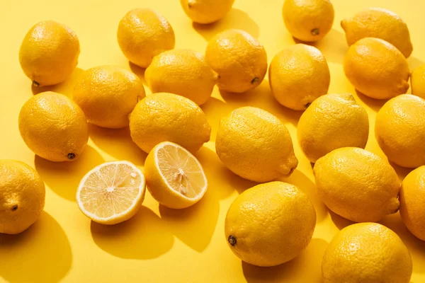 Corte maduro y limones enteros sobre fondo amarillo - foto de stock