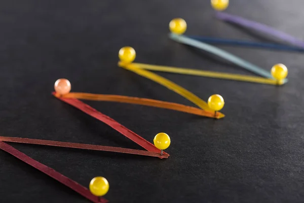Selective focus of multicolored abstract connected lines with pins on black background, connection and communication concept — Stock Photo