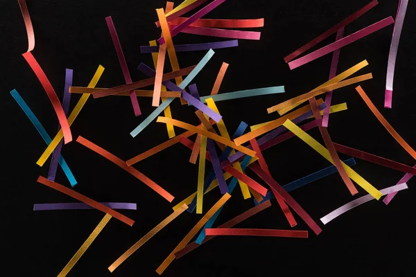 Vue de dessus de lignes abstraites multicolores dispersées isolées sur fond noir, concept de connexion et de communication — Photo de stock
