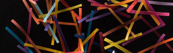 Vista superior de líneas abstractas multicolores dispersas sobre fondo negro, conexión y concepto de comunicación - foto de stock