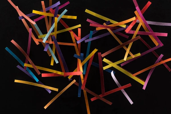 Vue de dessus de lignes abstraites multicolores dispersées isolées sur fond noir, concept de connexion et de communication — Photo de stock