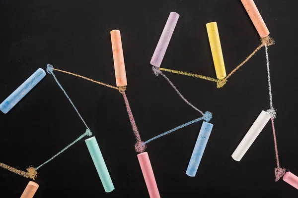 Top view of colorful chalk on black surface with connected drawn lines, connection and communication concept — Stock Photo