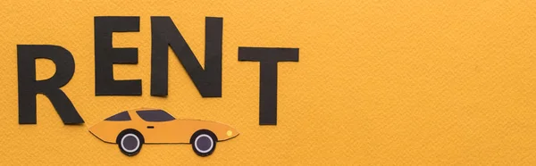 Top view of paper cut car and black rent lettering on orange background with copy space, panoramic shot — Stock Photo
