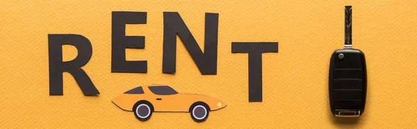 Draufsicht auf Papier geschnittenes Auto, Schlüssel und schwarzer Rent-Schriftzug auf orangefarbenem Hintergrund, Panoramaaufnahme — Stockfoto