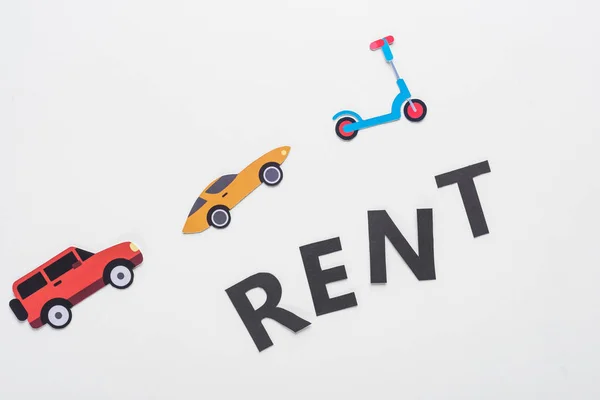 Top view of paper cut vehicles and black rent lettering on white background — Stock Photo