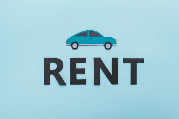 Draufsicht auf Papier geschnittenes Auto und schwarzer Rent-Schriftzug auf blauem Hintergrund — Stockfoto