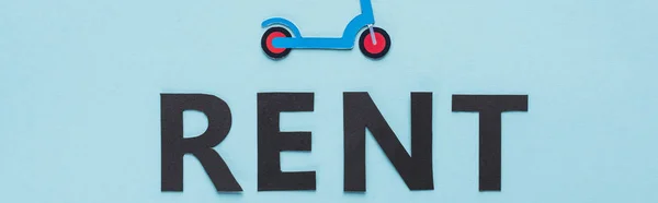 Vue du dessus du scooter de coup de pied de coupe de papier et lettrage de loyer noir sur fond bleu, vue panoramique — Photo de stock