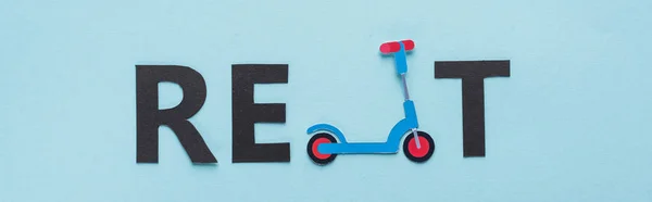 Top view of paper cut kick scooter and black rent lettering on blue background, panoramic shot — Stock Photo