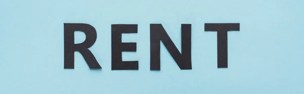 Von oben auf Papier geschnittener schwarzer Mietschriftzug auf blauem Hintergrund, Panoramaaufnahme — Stockfoto