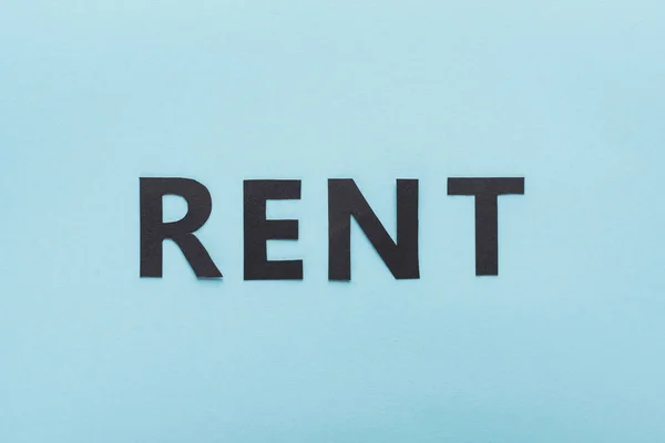 Top view of paper cut black rent lettering on blue background — Stock Photo