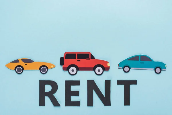 Draufsicht auf Papier geschnitten verschiedene Autos und Rent-Schriftzug auf blauem Hintergrund — Stockfoto