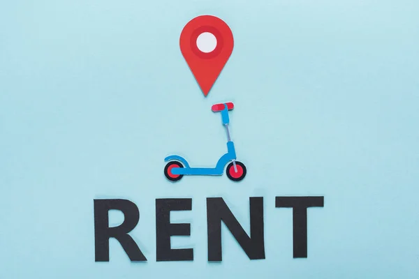 Top view of paper cut kick scooter with location mark near black rent lettering on blue background — Stock Photo