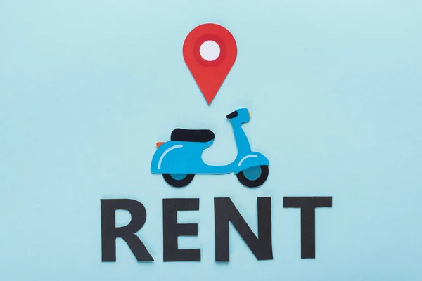 Top view of paper cut scooter with location mark near black rent lettering on blue background — Stock Photo