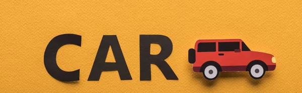 Top view of paper cut car and black lettering on orange background, panoramic shot — Stock Photo