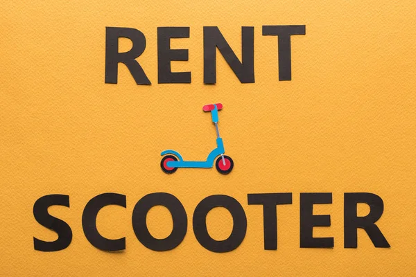 Vue du dessus du papier coupé louer scooter lettrage sur fond orange — Photo de stock