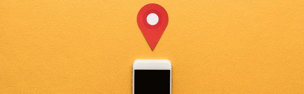 Vista superior de la marca de ubicación de corte de papel cerca del teléfono inteligente con pantalla en blanco sobre fondo naranja, plano panorámico - foto de stock