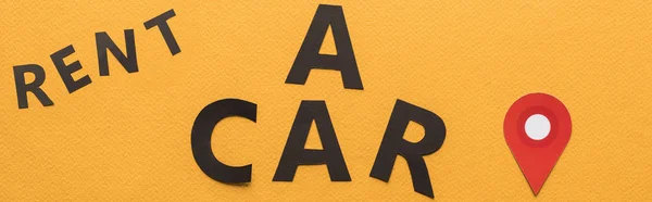 Vue du dessus du papier coupé louer une voiture lettrage avec marque de localisation sur fond orange, panoramique — Photo de stock