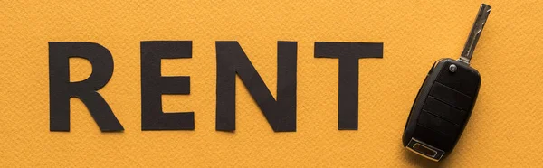 Vue du dessus du papier coupé louer lettrage et clé de voiture sur fond orange, vue panoramique — Photo de stock