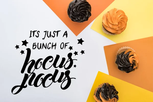 Vista superior de deliciosos cupcakes de Halloween no fundo amarelo, laranja e branco com ele é apenas um monte de ilustração hocus pocus — Fotografia de Stock