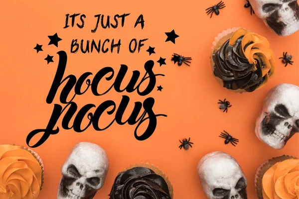 Vista superior de cupcakes, calaveras decorativas y arañas sobre fondo naranja con él es solo un montón de hocus pocus ilustración - foto de stock