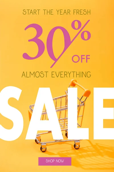 Pequeño carrito de compras vacío sobre fondo naranja brillante con 30 por ciento de ilustración de venta - foto de stock