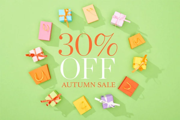 Round frame of decorative gift boxes and shopping bags on green background with 30 percent off autumn sale illustration — Stock Photo