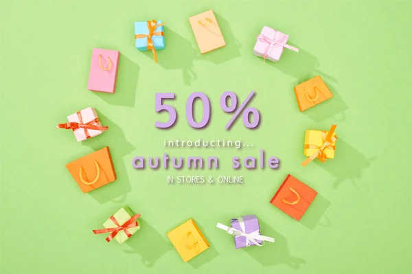 Armação redonda de caixas de presente decorativas e sacos de compras no fundo verde com 50 por cento de desconto na ilustração de venda de outono — Fotografia de Stock