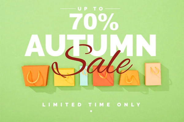 Vista superior de bolsas de compras coloridas decorativas sobre fondo verde con 70 por ciento de descuento ilustración venta otoño - foto de stock