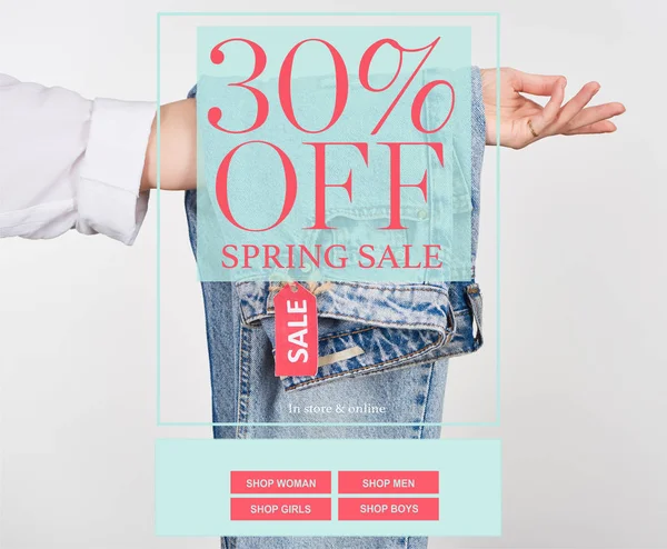 Vista ritagliata di donna che tiene appeso jeans con etichetta di vendita isolato su bianco con vendita primavera 30 per cento di sconto illustrazione — Foto stock