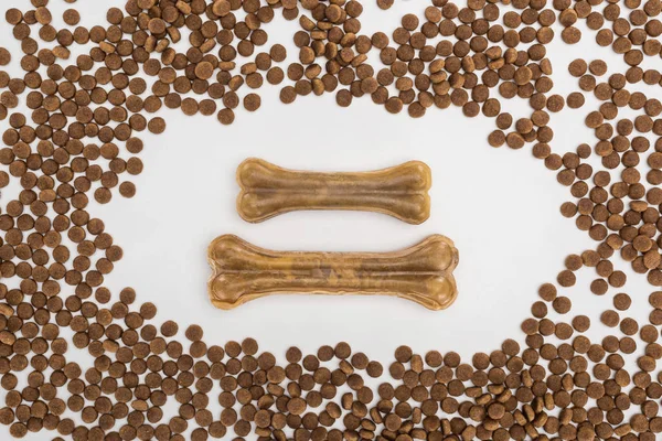 Top view of dry pet food scattered around bones isolated on white — Stock Photo