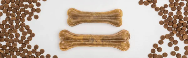 Vista superior de alimentos secos para mascotas dispersos alrededor de huesos aislados en blanco, plano panorámico - foto de stock