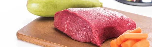Vista de perto de carne crua, cenoura e abobrinha em tábua de corte de madeira isolada em branco, tiro panorâmico — Fotografia de Stock