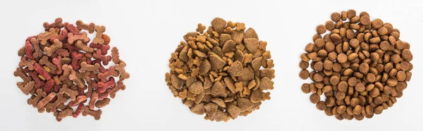 Top view of assorted dry pet food in piles isolated on white, panoramic shot — Stock Photo