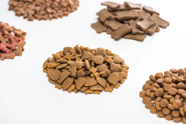 Selective focus of fresh assorted dry pet food in piles isolated on white — Stock Photo