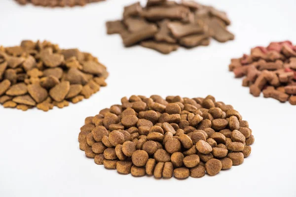 Selective focus of fresh assorted dry pet food in piles isolated on white — Stock Photo