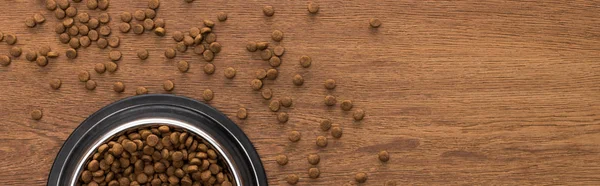 Top view of dry pet food in silver bowl on wooden table, panoramic shot — Stock Photo