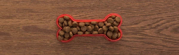Vista superior de comida seca para mascotas en hueso sobre mesa de madera, plano panorámico - foto de stock